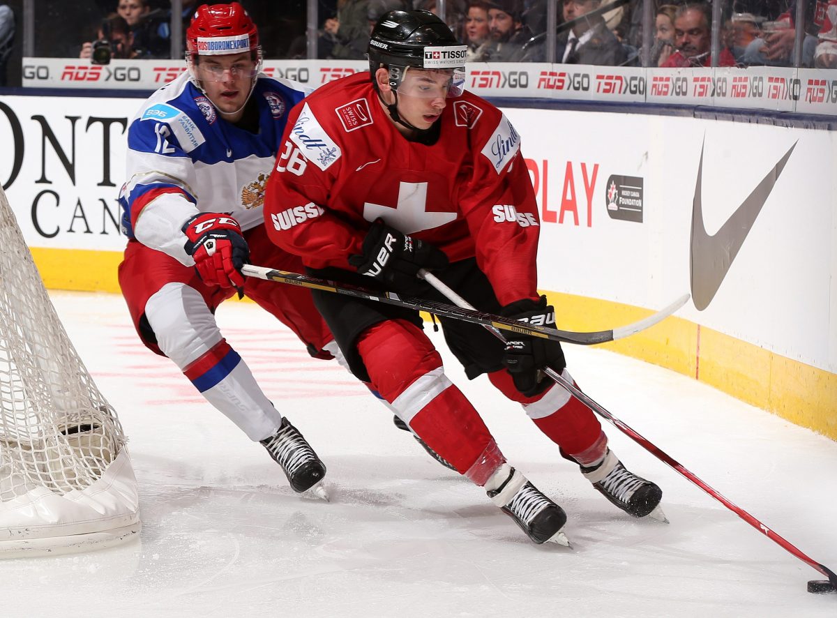 Switzerland's Noah Rod #26 plays the puck during preliminary round action at the 2015 IIHF World Junior Championship. (Photo by Andre Ringuette/HHOF-IIHF Images)