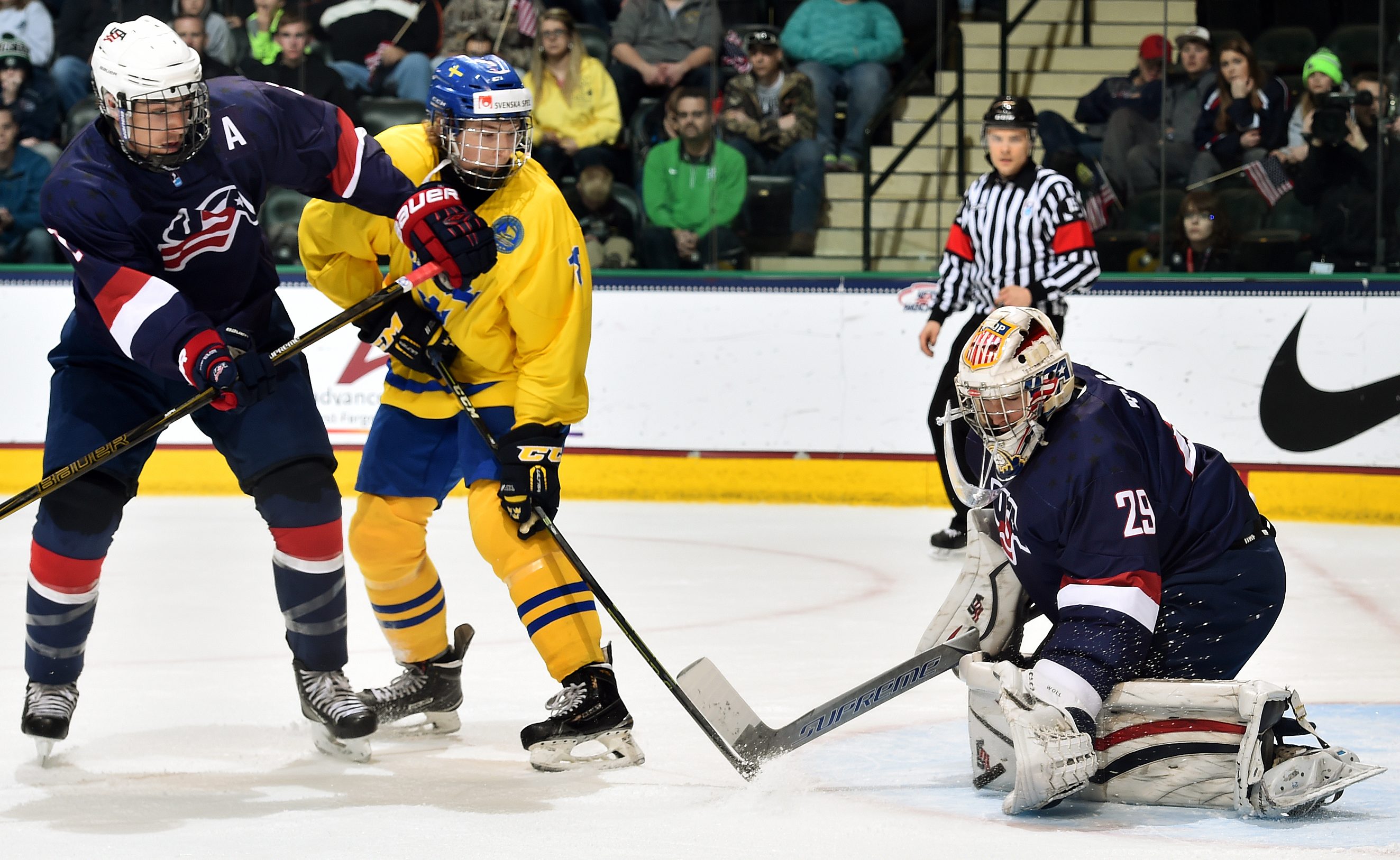 GRAND FORKS, NORTH DAKOTA - APRIL 16: USA's Joseph Woll #29 goes down to make the glove save while Luke Martin #2 keeps close watch on Sweden's Marcus Davidsson #18 during preliminary round action at the 2016 IIHF Ice Hockey U18 World Championship. (Photo by Minas Panagiotakis/HHOF-IIHF Images)