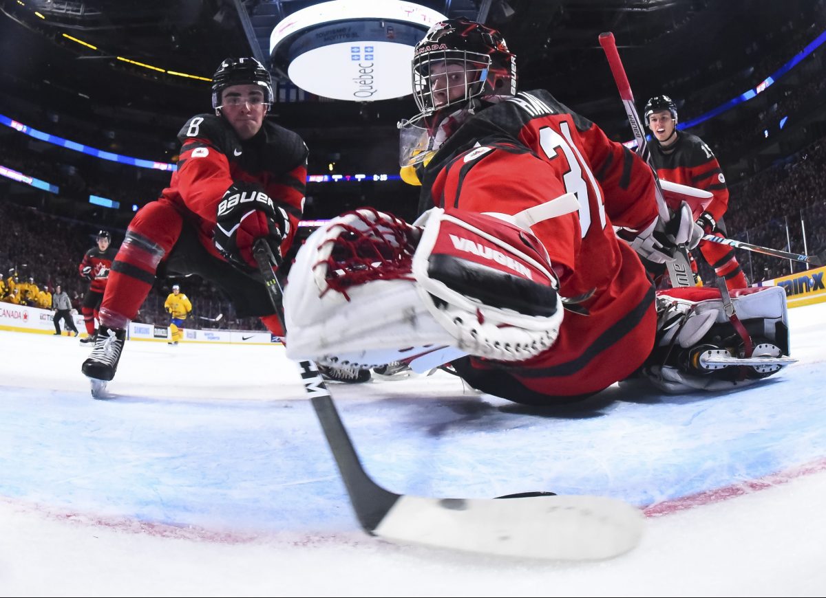 MONTREAL, CANADA - JANUARY 4: Canada's Dante Fabbro #8 stops the puck from crossing over the goal line while his goalie Carter Hart #31 dives to make the save during semifinal round action at the 2017 IIHF World Junior Championship. (Photo by Matt Zambonin/HHOF-IIHF Images)