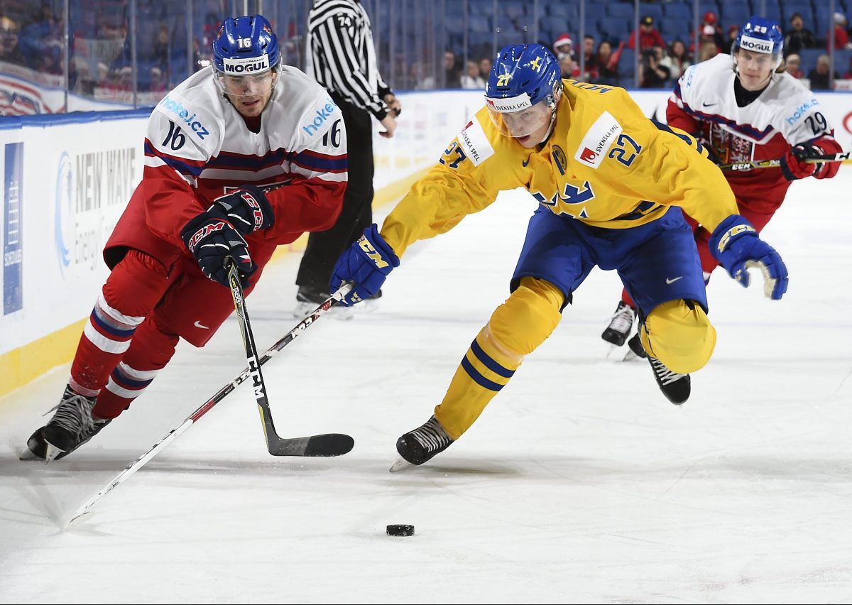 BUFFALO, NEW YORK - DECEMBER 28: The Czech Republic's Martin Kaut #16 skates with the puck while Sweden's Jacob Moverare #27 chases him down during preliminary round action at the 2018 IIHF World Junior Championship. (Photo by Matt Zambonin/HHOF-IIHF Images)