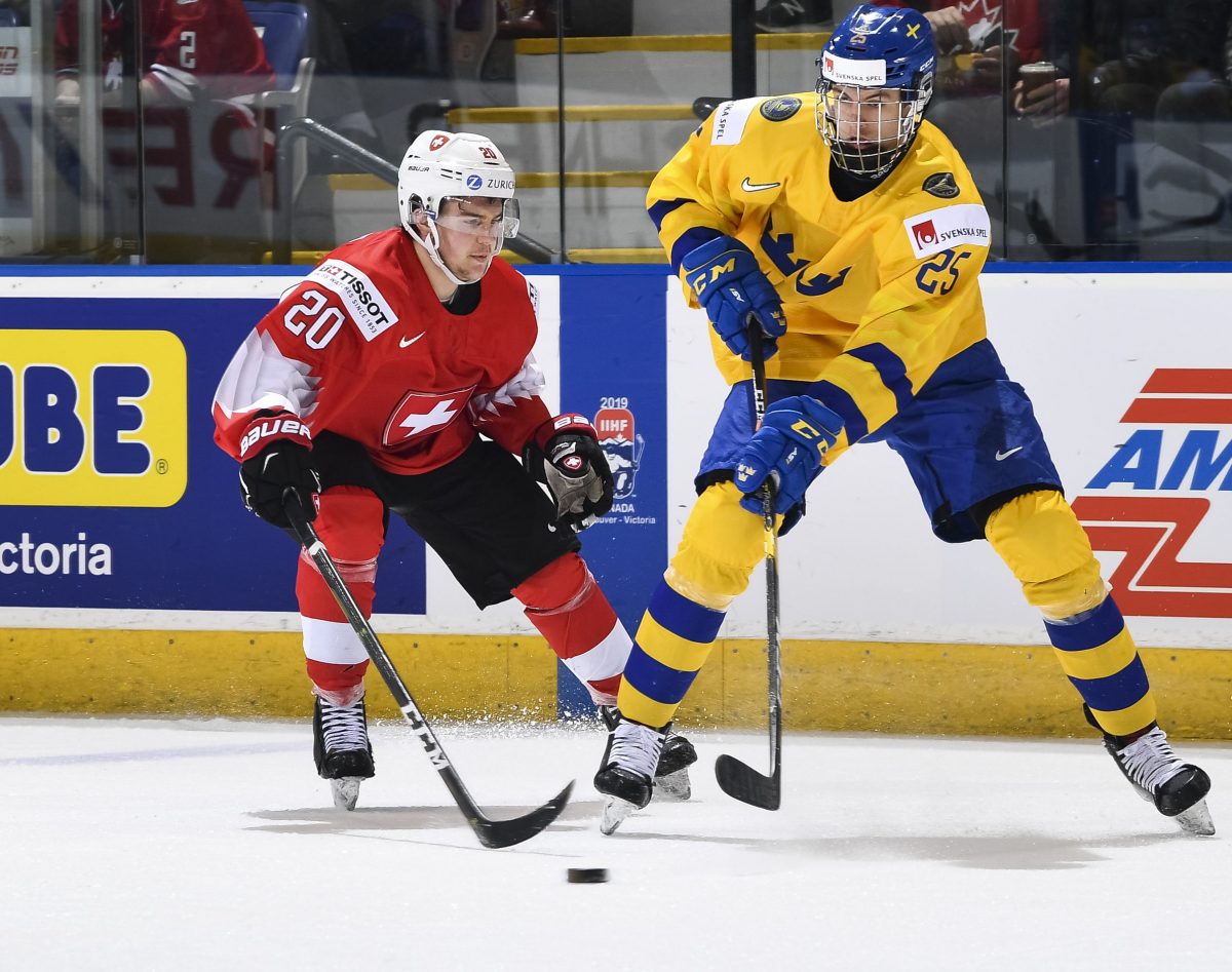 VICTORIA, BC - JANUARY 2: Switzerland's Ramon Tanner #20 battles for the puck with Sweden's Philip Broberg #25 during quarterfinal round action at the 2019 IIHF World Junior Championship at Save-On-Foods Memorial Centre on January 2, 2019 in Victoria, BC Canada. (Photo by Minas Panagiotakis/HHOF-IIHF Images)
