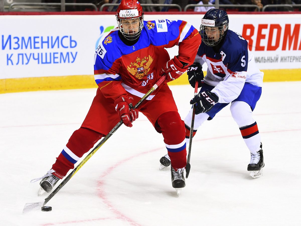 CHELYABINSK, RUSSIA - APRIL 24: Russia's Yegor Spiridonov #7 plays the puck while Slovakia's Alexander Zekucia #5 defends during preliminary round action at the 2018 IIHF Ice Hockey U18 World Championship. (Photo by Andrea Cardin/HHOF-IIHF Images)