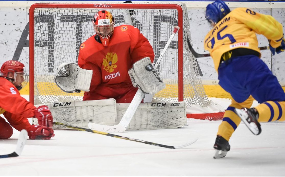 ORNSKOLDSVIK, SWEDEN - APRIL 23: Russia’s Yaroslav Askarov #1 attempts to make a blocker save against Sweden’s Simon Holmstrom #25 while Semyon Chistyakov #6 defends during preliminary round action at the 2019 IIHF Ice Hockey U18 World Championship at Fjallraven Center on April 23, 2019 in Ornskoldsvik, Sweden. (Photo by Steve Kingsman/HHOF-IIHF Images)